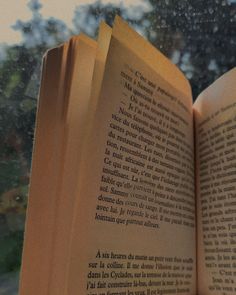 an open book sitting on top of a window sill next to a rain soaked window