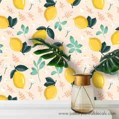 there is a vase with lemons on the wall next to a potted plant