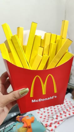 a woman holding up a box of french fries in front of a table with other items on it