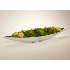 a bowl filled with green plants on top of a white table