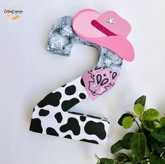 a paper cowgirl hat and bandana laying on top of a white table next to some plants