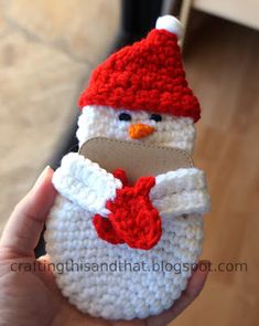 a hand holding a small crocheted snowman cell phone case