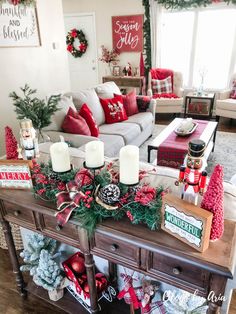 a living room decorated for christmas with red and green decorations on the coffee table, couches, and candles