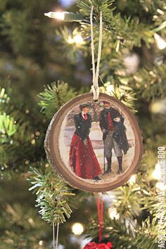 an ornament hanging from a christmas tree with two people in the snow on it