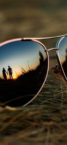 the reflection of two people in sunglasses is seen through the lens of another person's eye