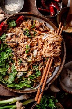 a bowl filled with noodles and vegetables next to chopsticks