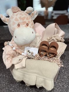 a giraffe stuffed animal sitting on top of a pile of clothing and shoes