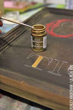 a person is painting on a canvas with gold paint