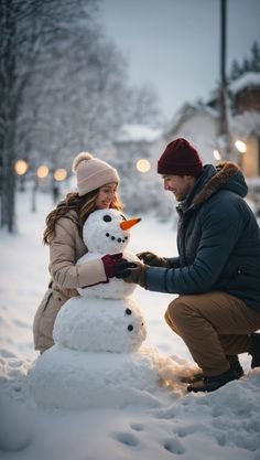 a man and woman building a snowman in the snow