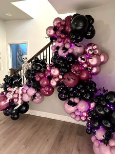 a bunch of balloons that are on the ground in front of a stair case with black, pink and white balloons