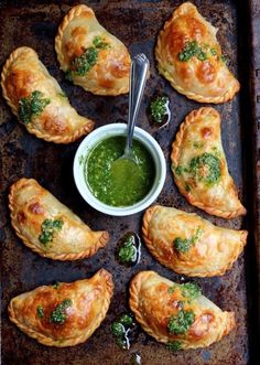 several pastries on a baking sheet with green sauce