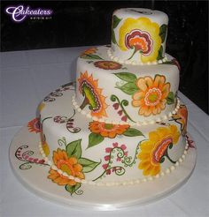 a three tiered cake decorated with flowers and pearls on a white tablecloth covered table