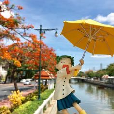 a figurine holding an umbrella next to a body of water