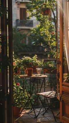 an open door leading to a balcony with potted plants on the table and chairs