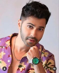 a man with a watch on his wrist and wearing a purple flowered shirt is looking at the camera