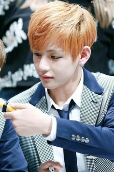 the young man is looking at his cellphone while wearing a suit jacket and tie