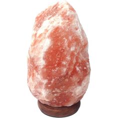 a large red rock sitting on top of a wooden stand next to a white wall