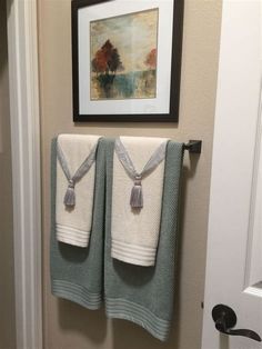 two towels are hanging on the wall in front of a framed painting and a door