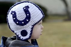 a little boy wearing a crocheted hat with a blue and white horseshoe on it