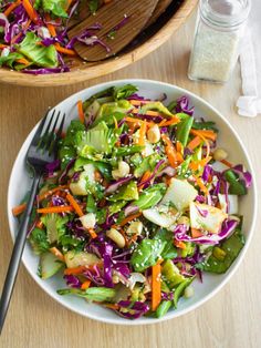 a salad with carrots, lettuce and other veggies in a bowl