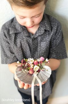 a young boy holding a flower arrangement in his hands