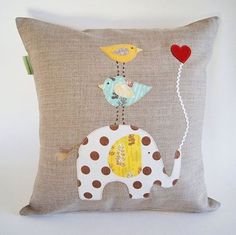 a pillow with an elephant, bird and balloon on it