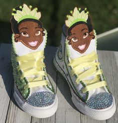 a pair of sneakers with princess and the frog on them are sitting on a wooden surface