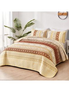 a bed covered in a yellow bedspread next to a potted palm tree