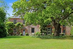 a large brick house surrounded by lush green trees