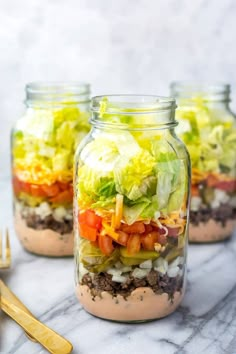 two mason jars filled with salad and dressing