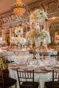 the tables are set up for a formal function with chandeliers and centerpieces