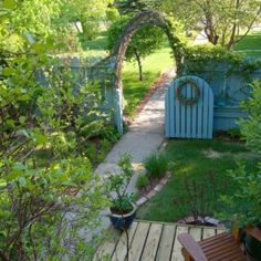 a wooden bench sitting on top of a lush green field next to a small garden