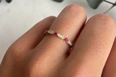 a woman's hand wearing a gold ring with pink and white stones on it