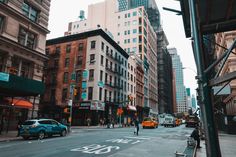 an empty city street with cars parked on both sides and tall buildings in the background