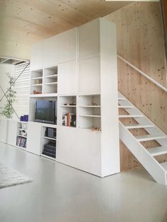 a living room filled with white furniture and a staircase leading up to the top floor