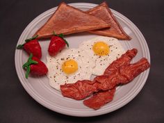 two eggs, toast, strawberries and bacon on a white plate with black background