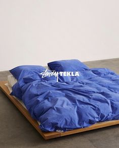 a bed with blue sheets on top of it and the word tata tekka written in white