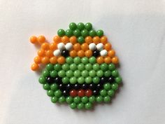 a beaded brooch with an orange, green and black design on it's face