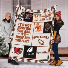 two women holding up a football themed blanket