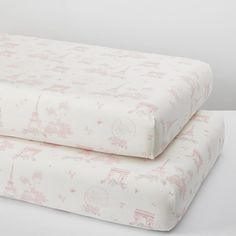 two sheets that have pink and white designs on them, one is folded up to the side