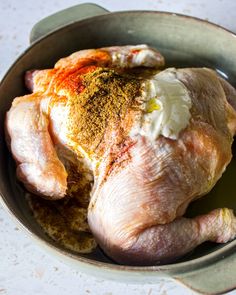 a raw chicken in a bowl with seasoning on top