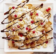 a white plate topped with waffles covered in ice cream and cherries next to bananas