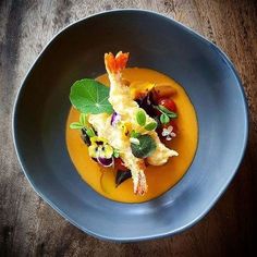 a blue plate topped with food and garnish on top of a wooden table