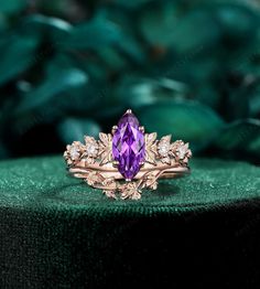 a ring with an amethorate and diamonds on it sitting on top of a green surface