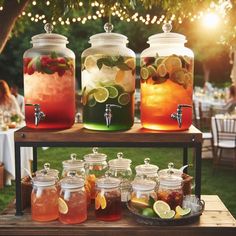 several jars filled with drinks sitting on top of a wooden table