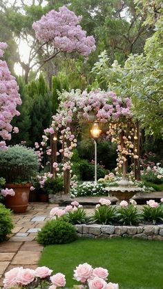 a garden with lots of flowers and plants around it, including pink roses on the trees