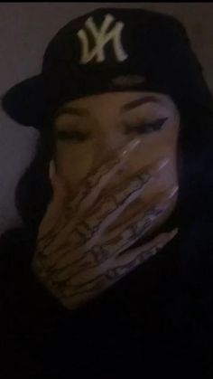 a woman wearing a yankees hat and covering her face with her hands in front of her mouth