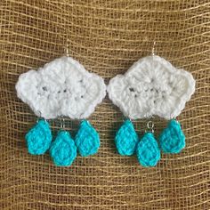 two crocheted earrings with blue tears on top of a piece of fabric