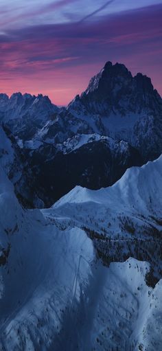 the mountains are covered in snow as the sun is setting over them and there is no image to describe