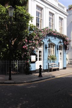 a blue and white building with pink flowers on it